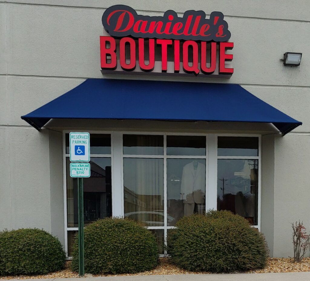 Storefront of Danielle's Boutique Bridal and Tuxedo Rentals, featuring a glass door and three small green bushes